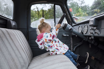 Side view of girl driving car