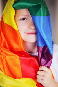 Portrait of boy covering himself with colorful scarf