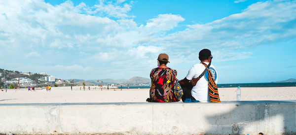 Rear view of people on beach against sky