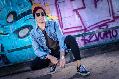 Full length of young man sitting on wall