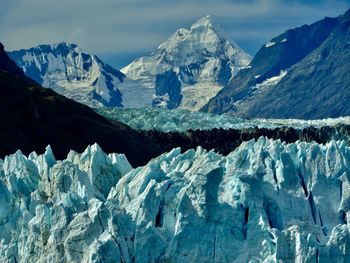 Scenic view of glacier and snowcapped mountains against sky