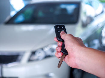 Midsection of man holding mobile phone in car