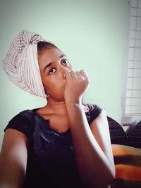 Portrait of girl looking away against wall at home