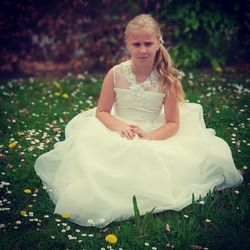 Portrait of girl in gown sitting on field