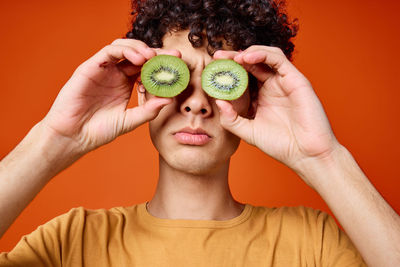 Portrait of young woman covering face with fruits