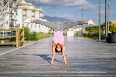 Woman doing handstand on boardwalk against sky