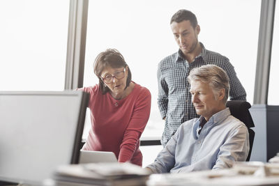 Business people using laptop at desk in office