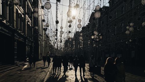 Group of people walking on illuminated street amidst buildings at night