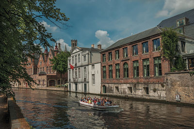 Boats in canal by buildings against sky