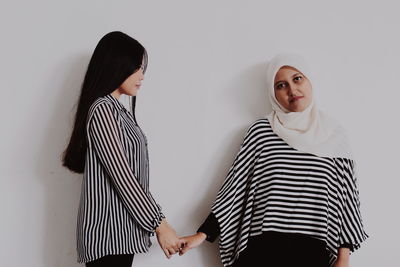 Portrait of woman with friend standing against red wall