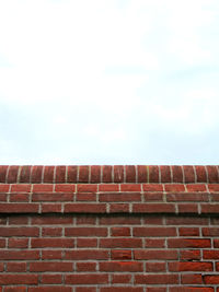 Low angle view of brick wall against sky