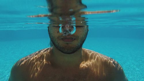 Portrait of shirtless man swimming in pool