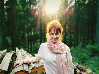 Portrait of smiling young woman standing against trees