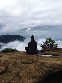 Rear view of woman sitting against sky