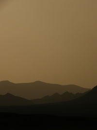 Scenic view of silhouette mountains during sunset