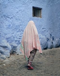 Rear view of woman covered by towel walking on footpath