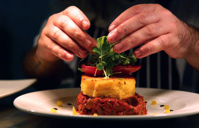 Midsection of chef garnishing food at table