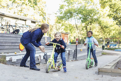 Teacher motivating children on push scooters during race