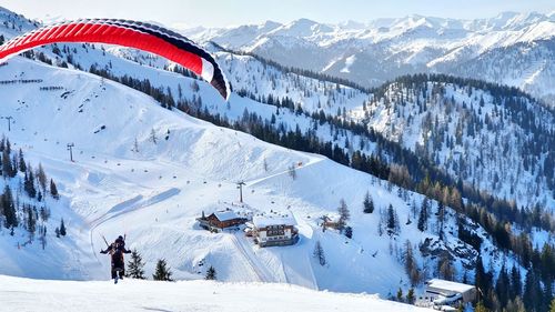 People paragliding on snow covered mountains during winter