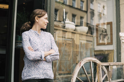 Confident owner with arms crossed standing outside store