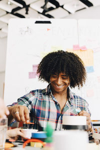 Smiling businessman working with businesswoman while sitting at table in creative office