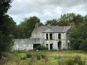 Abandoned building by trees against sky