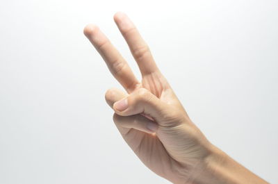 Close-up of hand holding hat against white background