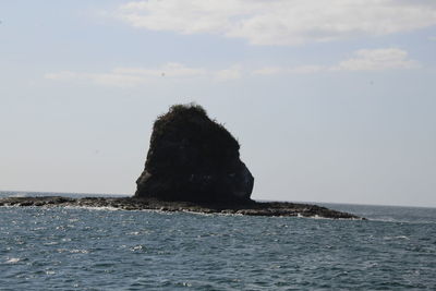 Rock formation in sea against sky