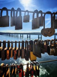 Close-up of padlocks hanging on metal against sky