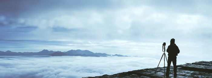 Rear view of man standing on mountain against sky