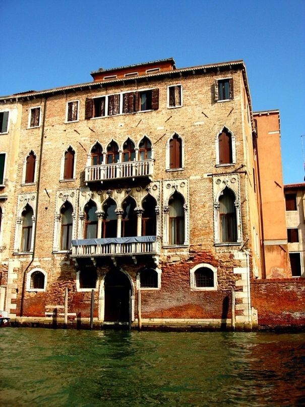 architecture, built structure, building exterior, clear sky, window, low angle view, facade, arch, building, history, blue, water, sunlight, outdoors, waterfront, no people, day, city, travel destinations, old