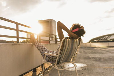 Young woman with headphones sitting on rooftop