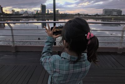 A girl is using a smartphone to take a landscape photo