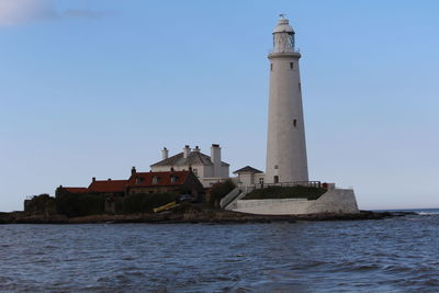 Lighthouse by sea against sky