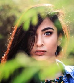 Portrait of young woman seen through plants in park