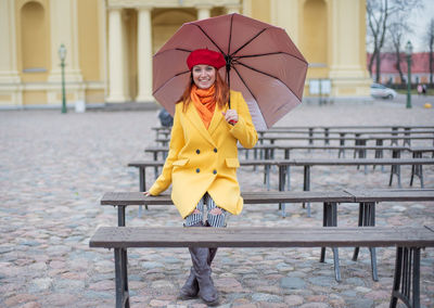 Woman with umbrella on bench in rainy season