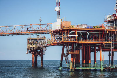 Metallic structure by sea against clear sky