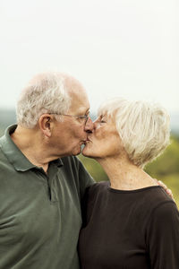 Affectionate senior couple kissing while standing against sky