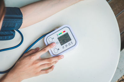 Midsection of woman checking blood pressure on table