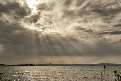 Sunlight streaming through clouds over sea