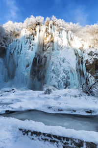 Scenic view of waterfall against sky during winter