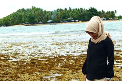 Rear view of woman standing at beach