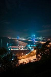 Illuminated bridge over river against sky at night