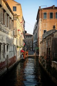 Canal amidst city against clear sky