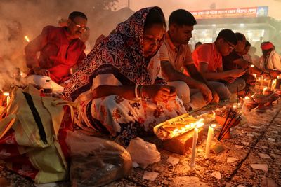 Women praying at rakher upobash infront of burning candle and incense