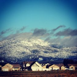 Houses by mountains against blue sky