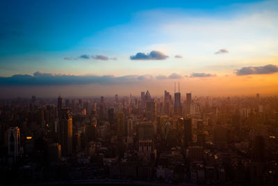 Aerial view of modern buildings in city against sky during sunset