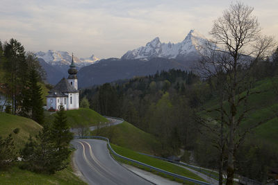 Road amidst trees and mountains against sky