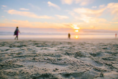 People on beach against sky during sunset