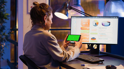 Rear view of woman using digital tablet while sitting at office